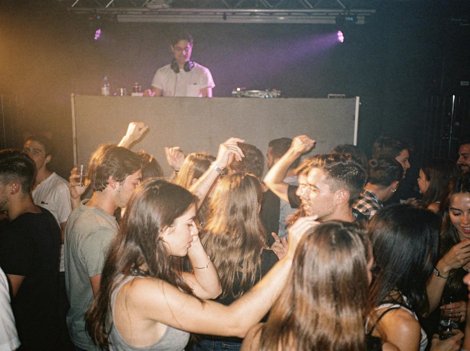 Crowd dancing to a deep log-drum groove from an afrobeats DJ in a dimly lit club