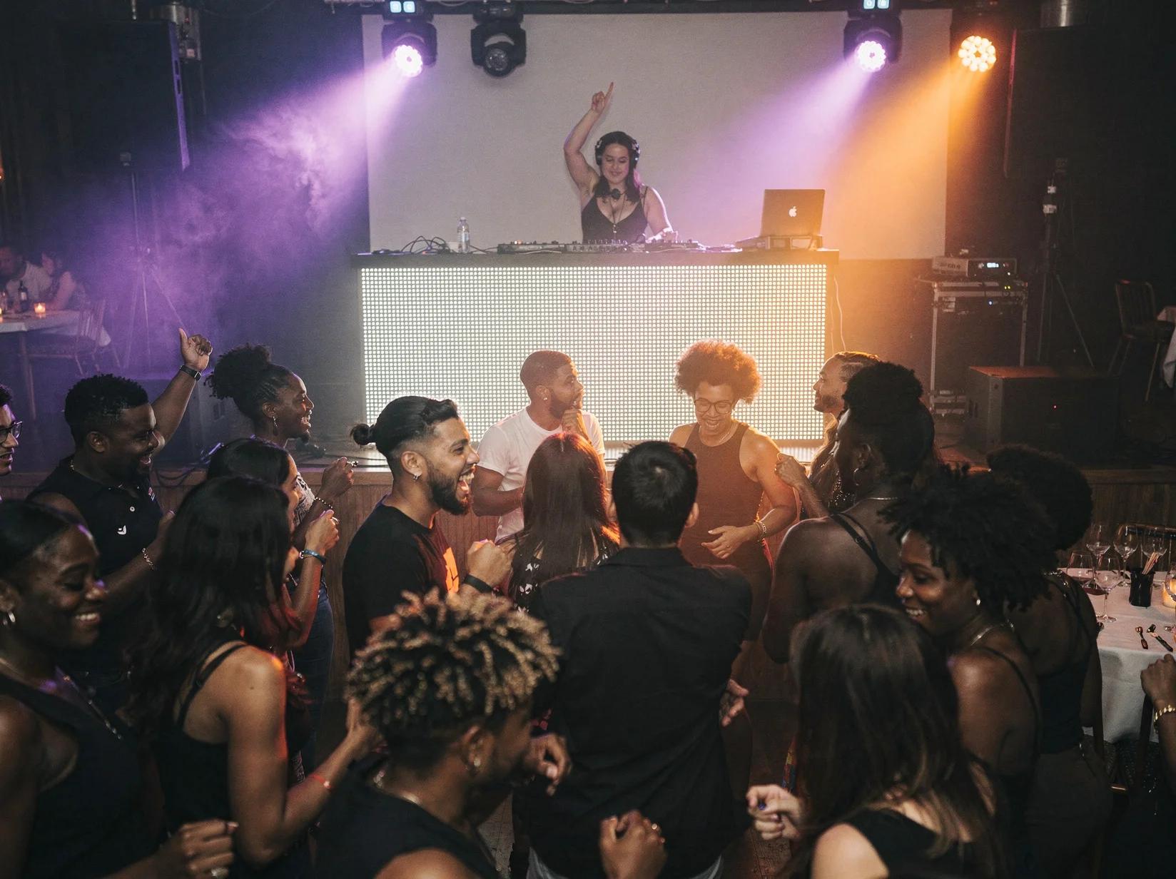 Afrobeats-DJ achter de booth terwijl een volle dansvloer uitbundig danst in een clubsfeer