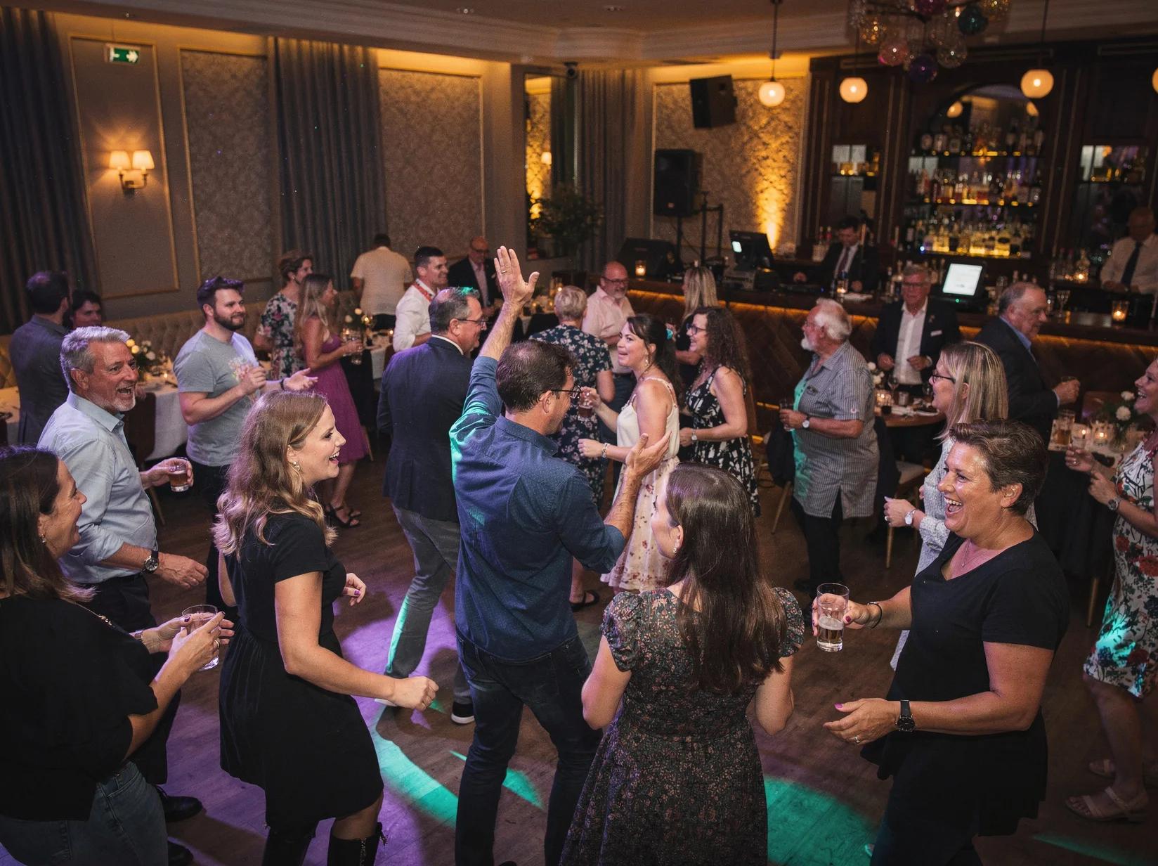 Gevarieerde dansende gasten op een feest waar een allround DJ iedereen op de dansvloer krijgt in een stijlvolle feestzaal.