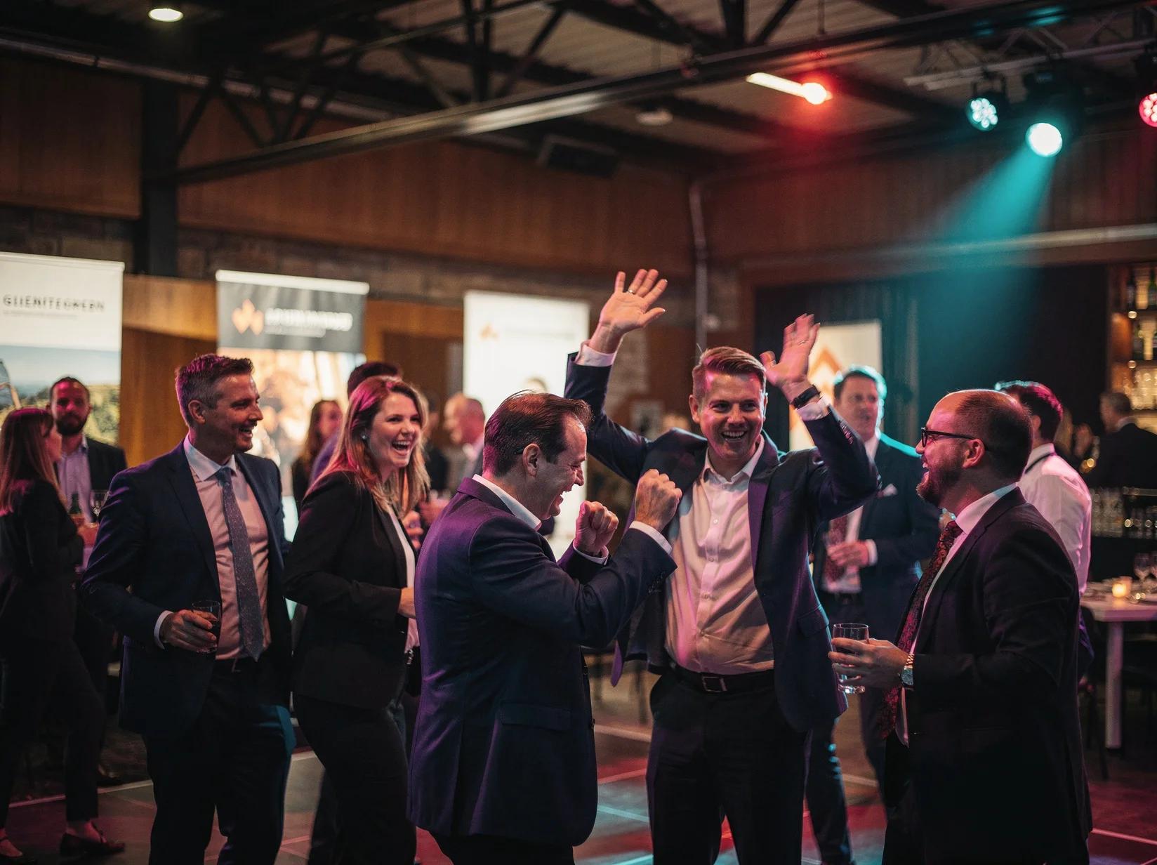 Professionals die dansen tijdens de afsluitende borrel van een beurs met een DJ die voor energie zorgt