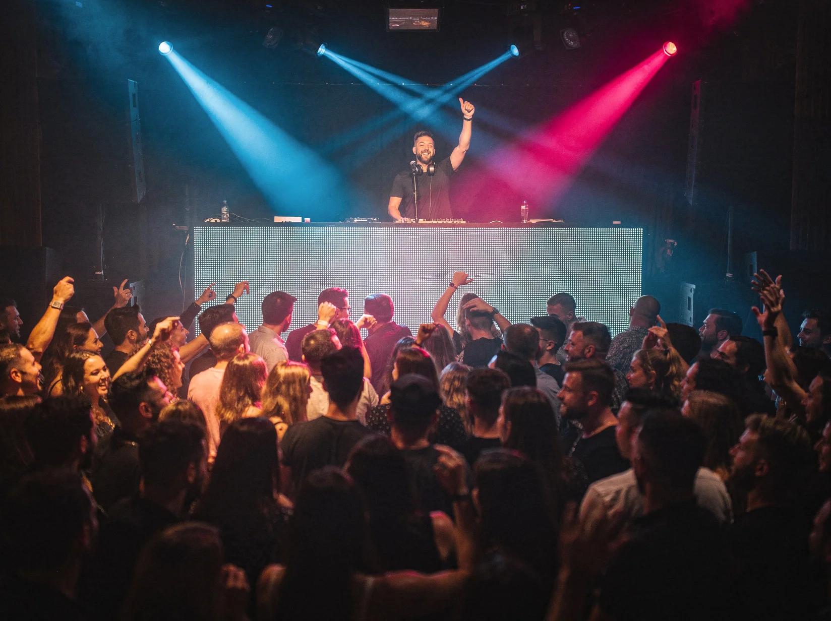 Professional club DJ playing to a packed dance floor at a European club night