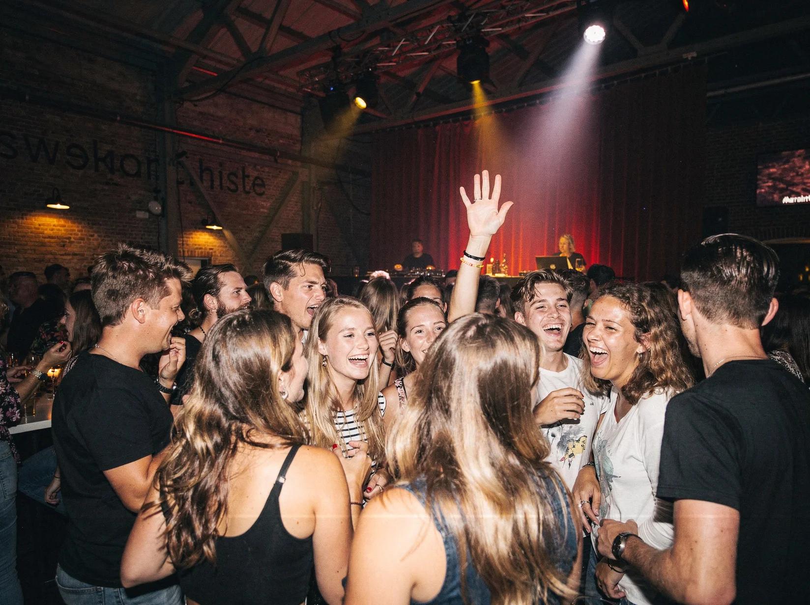 Gasten dansen uitgelaten op een feest met een DJ in Arnhem.