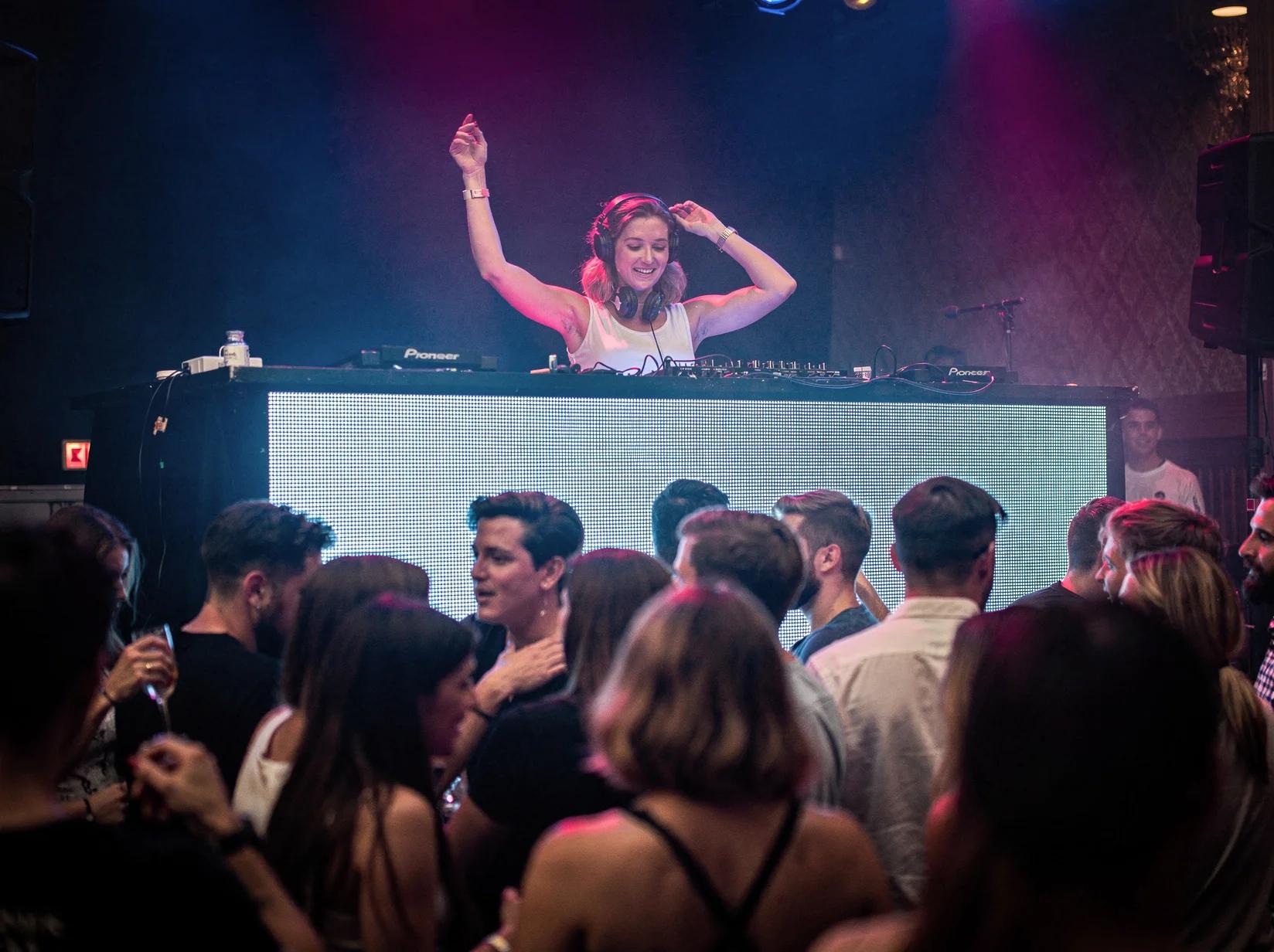 Energieke DJ achter de booth met dansend publiek waar je een DJ kunt huren in Gent