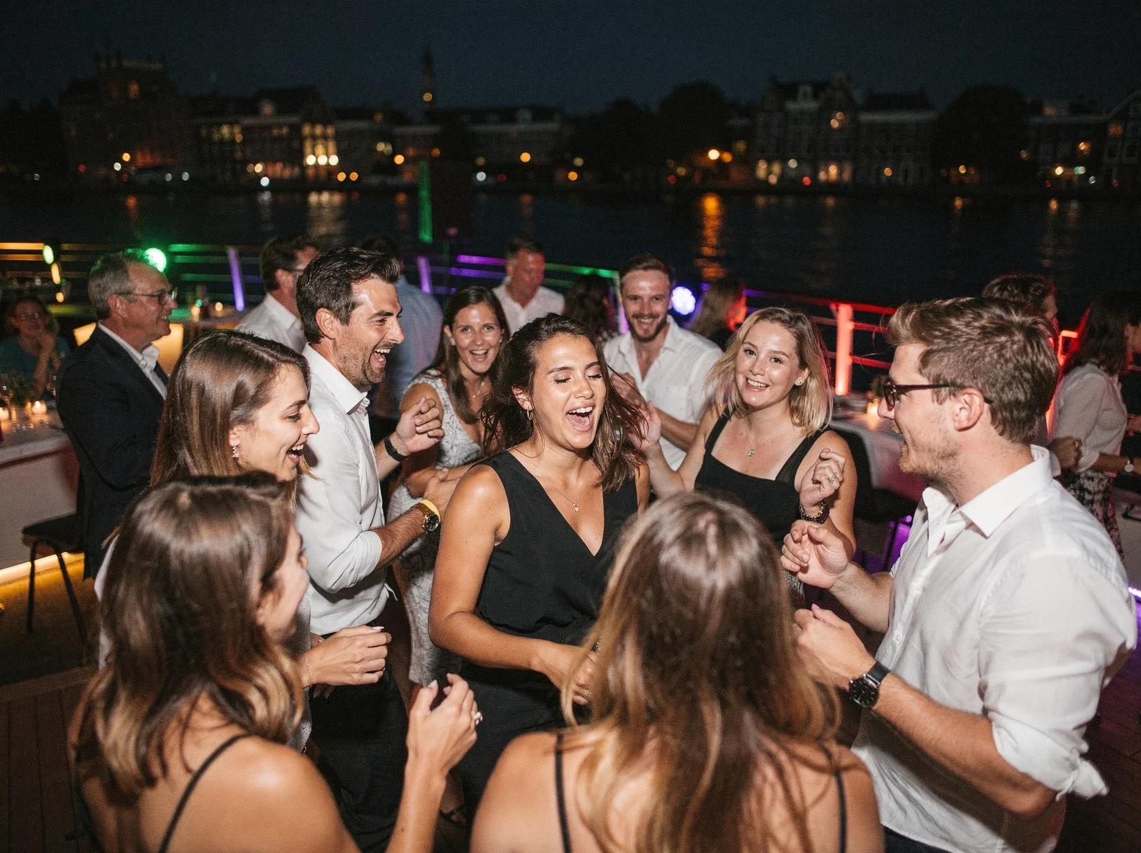 Collega's dansen op een boot aan het water wanneer ze een DJ huren in Dordrecht