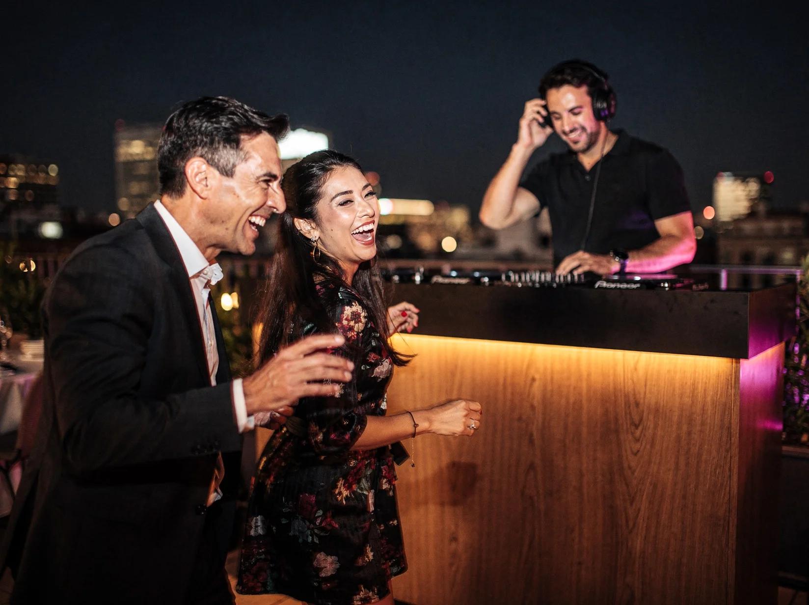 Guests laughing and dancing at a Madrid rooftop event with a DJ booked across Spain through party.dj