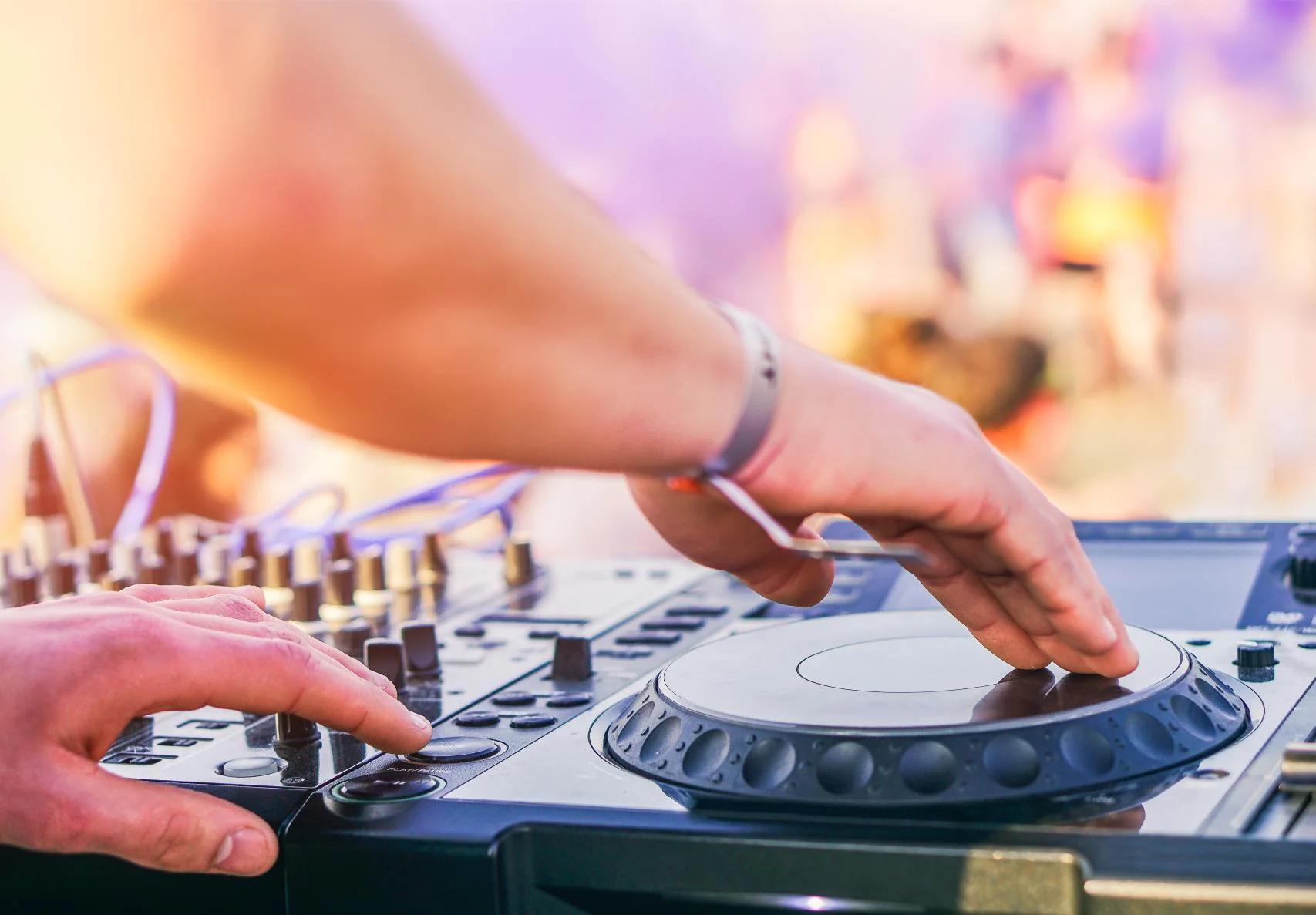 DJ bedient professioneel mengpaneel met draaitafels tijdens live party performance met paarse en gele verlichting.
