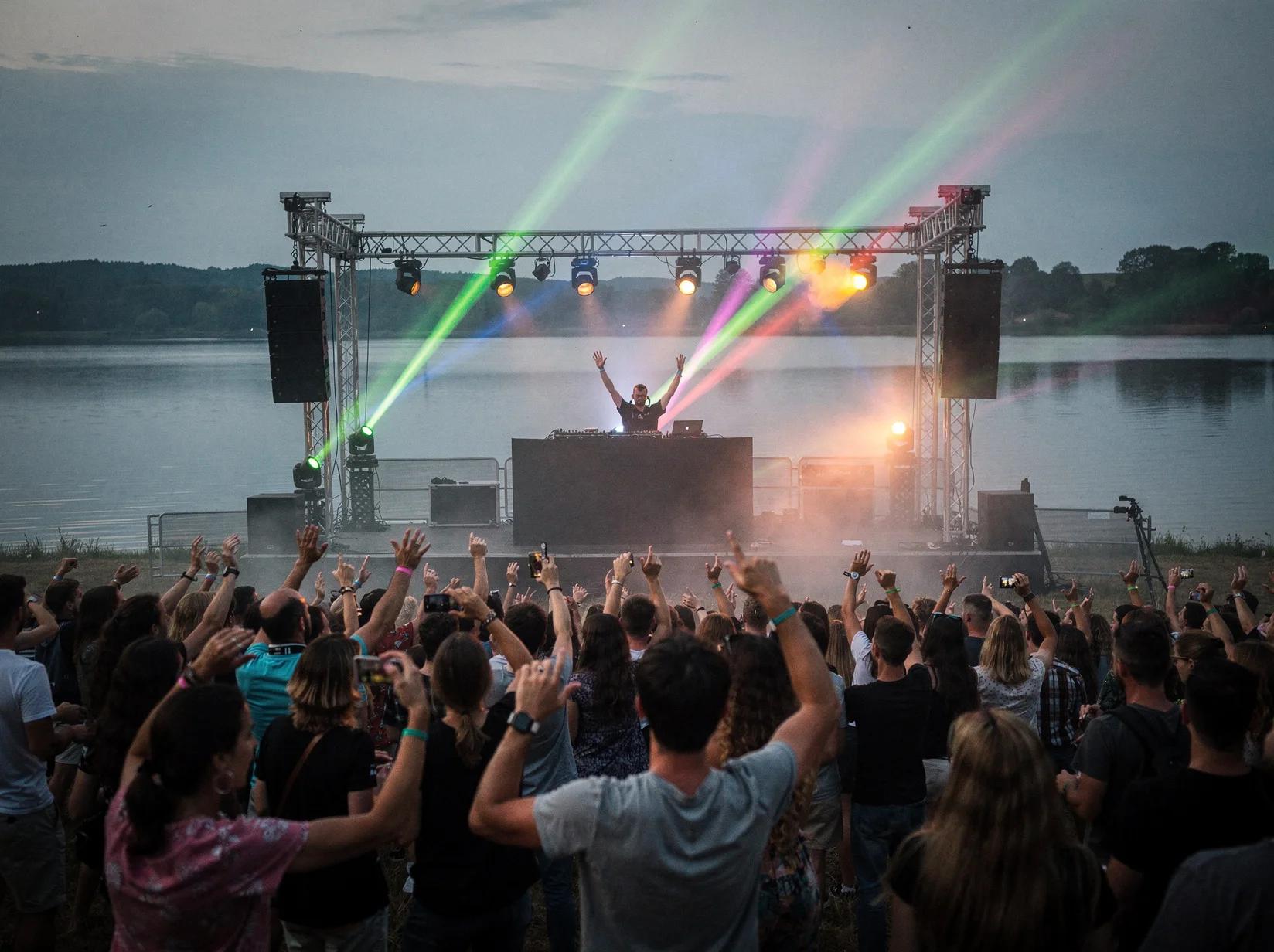 Large festival crowd dancing in front of a stage at a European drum & bass festival at dusk