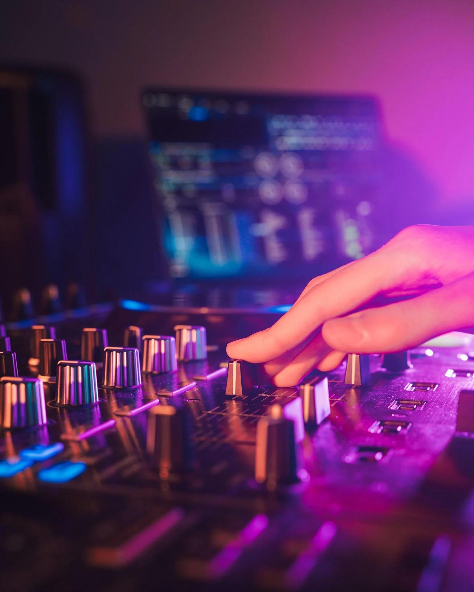 DJ bedient professionele mixer en controllers met neonverlichting tijdens een feest. Zorg dat je je favoriete DJ op tijd boekt.