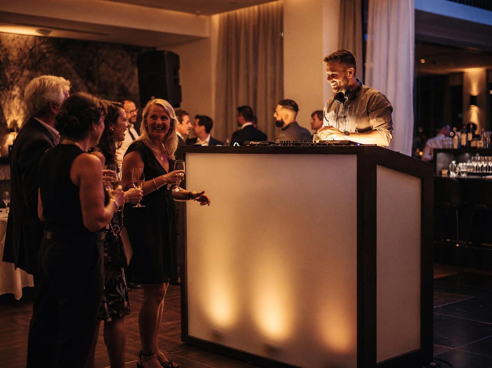 Lounge-DJ achter een strakke booth zorgt voor sfeervolle achtergrondmuziek tijdens een stijlvolle receptie