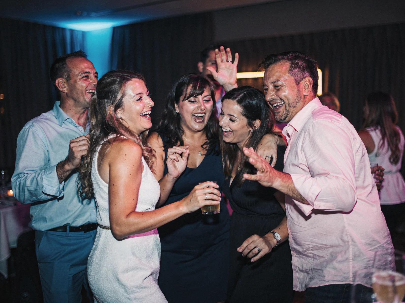 Vrienden dansen dicht bij elkaar op een gezellig privéfeest in het schijnsel van gekleurde feestverlichting
