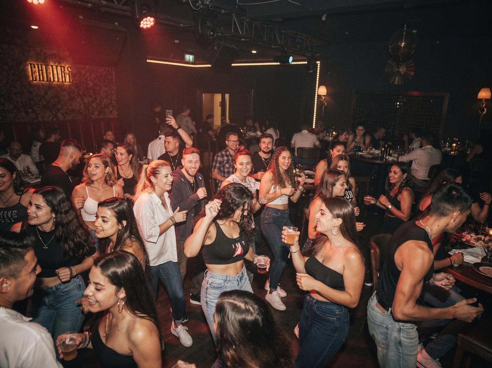 Young energetic crowd dancing together at a packed reggaeton DJ night in a club