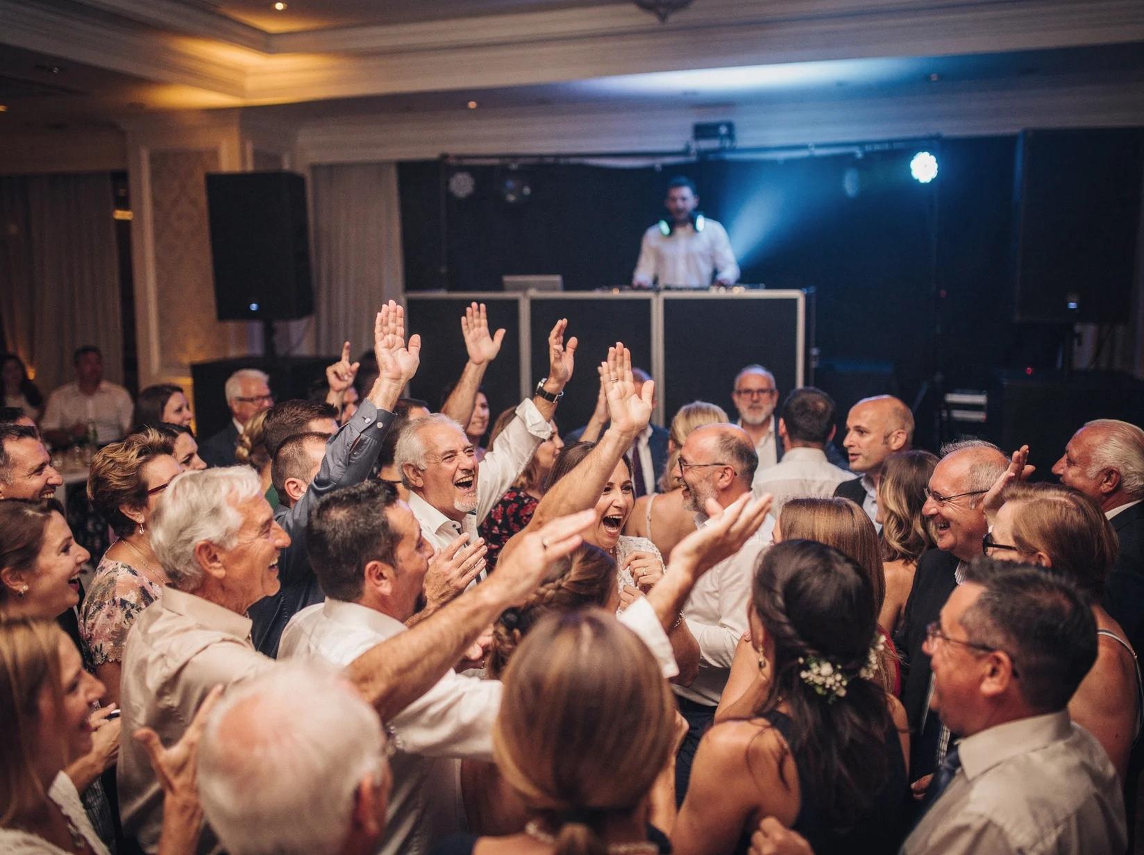 A rock DJ keeps a wedding floor roaring as a mixed-age crowd sings along together