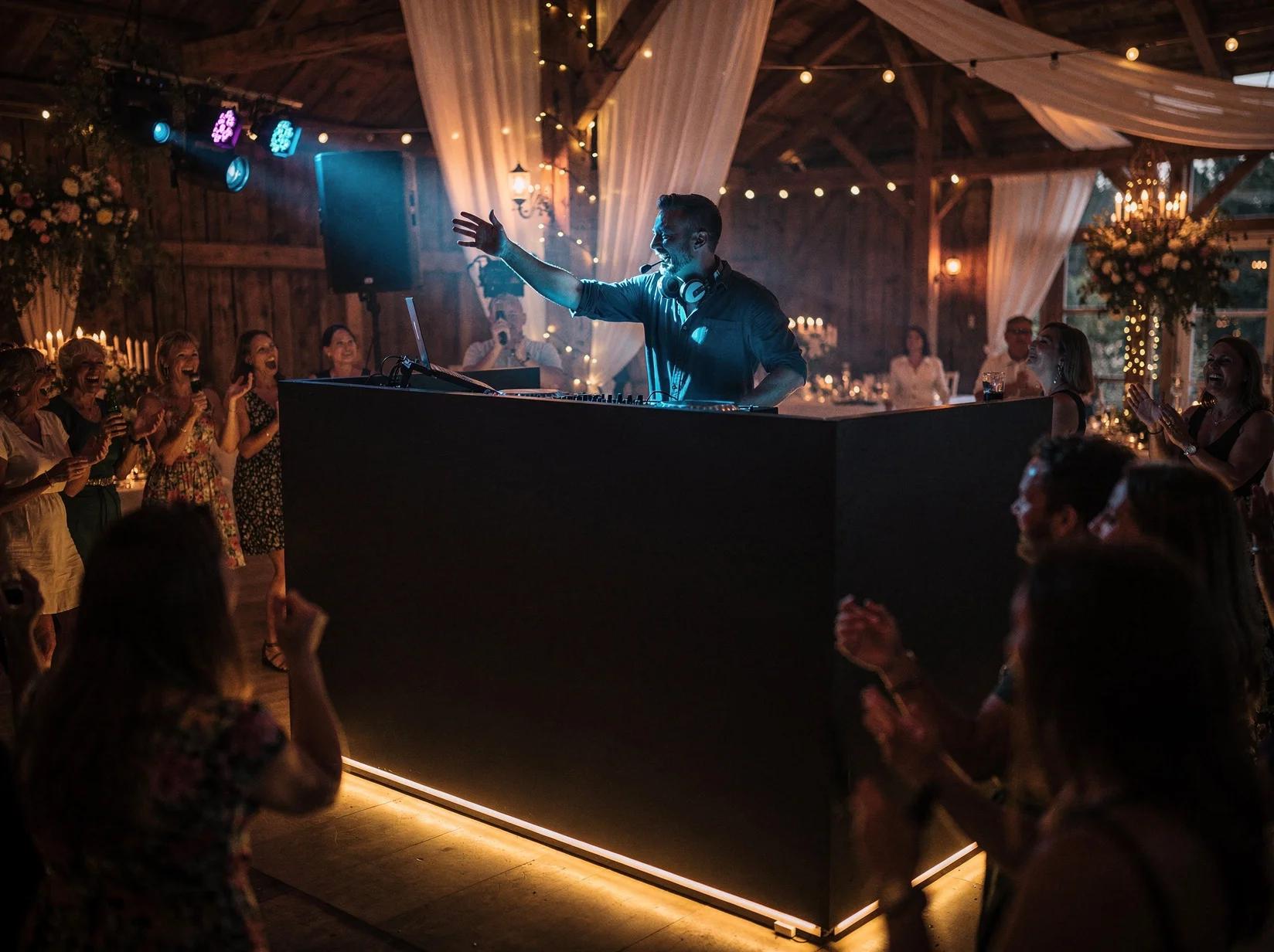 Rock-DJ met koptelefoon achter een strakke booth die een meezingende feestzaal opzweept