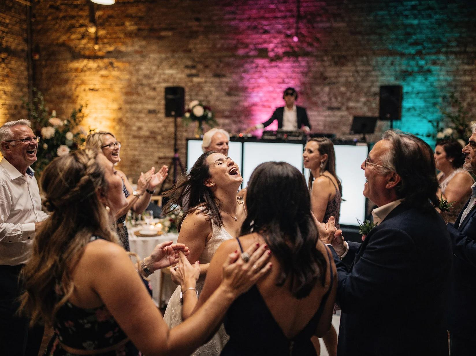 Wedding guests roaring along to a rock DJ set on a warm lit dance floor