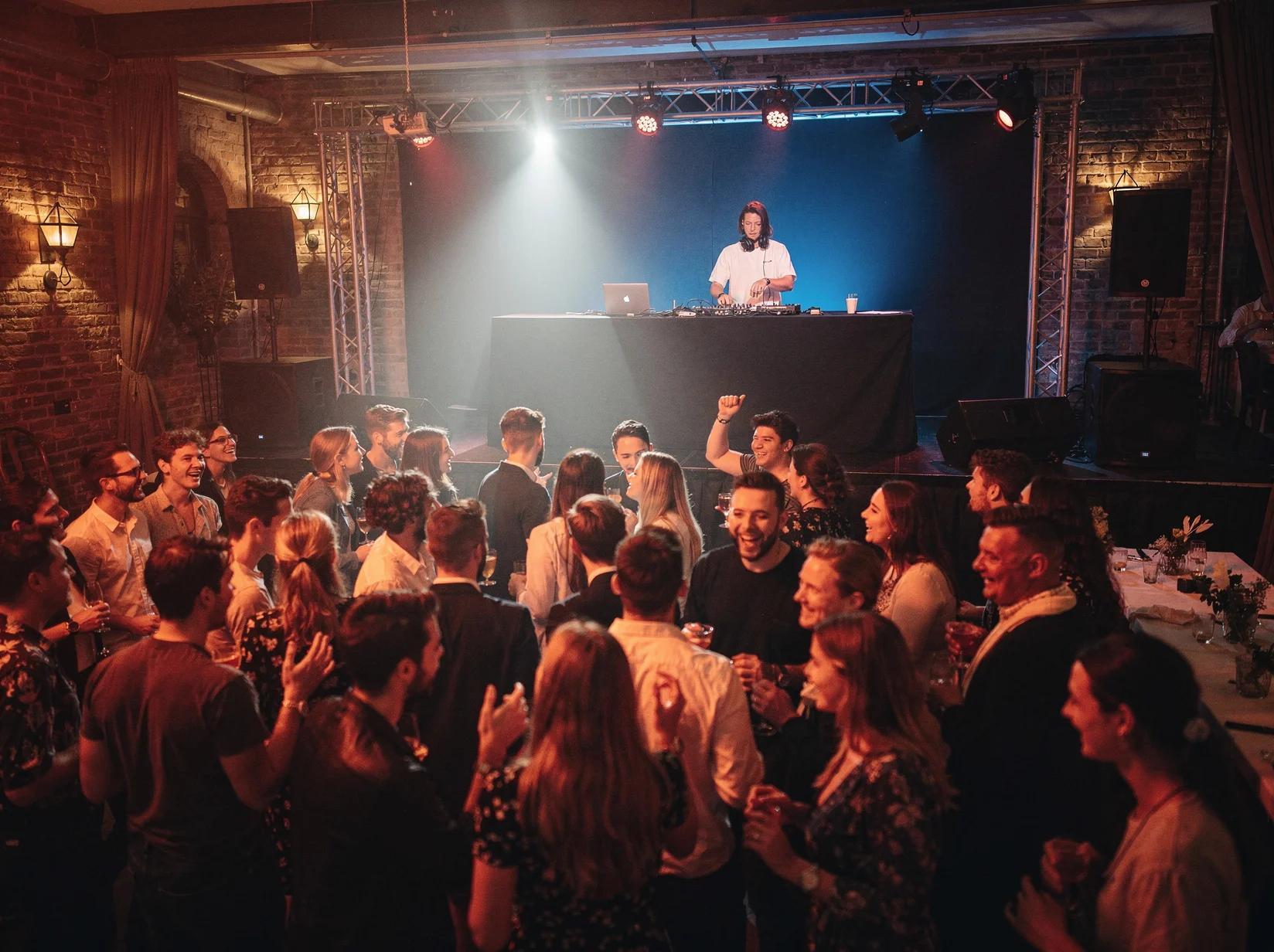 Volle dansvloer op een studentenfeest in een sociëteit met een DJ achter de booth en warm feestlicht