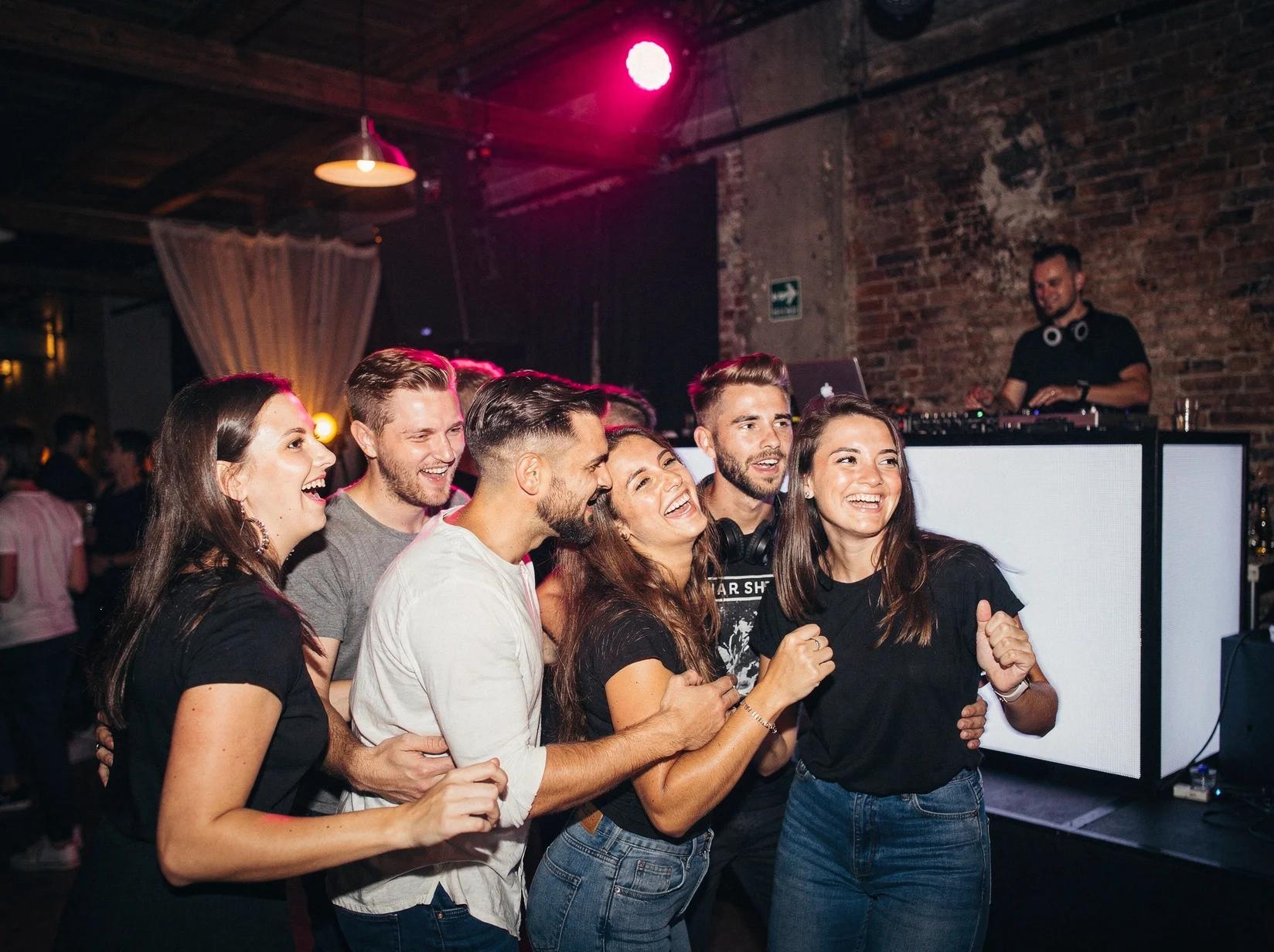 Groep vrienden danst uitgelaten tijdens een trance-feest in een sfeervolle industriële zaal