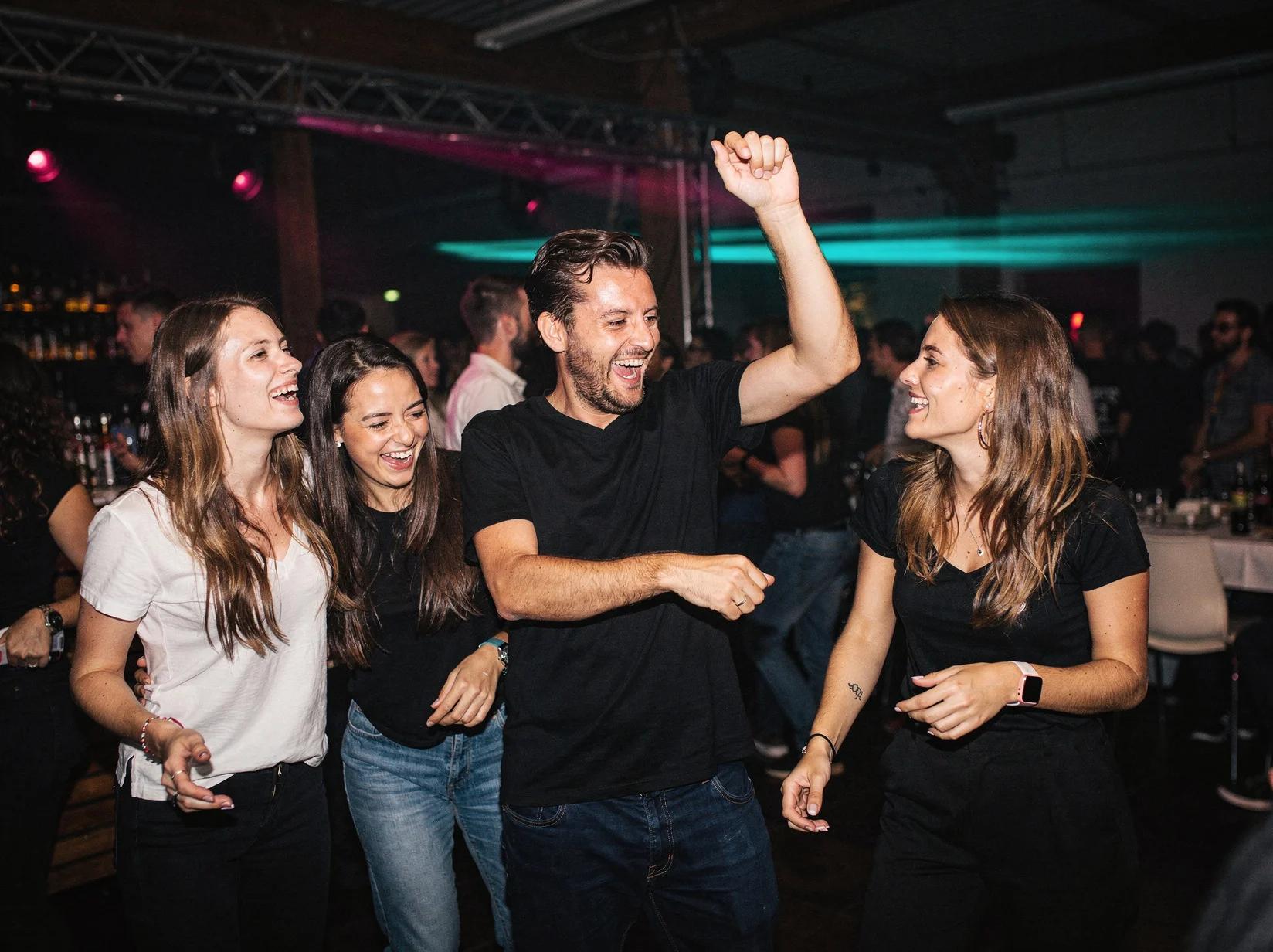 Friends dancing together in a euphoric moment at a trance DJ night in an industrial venue