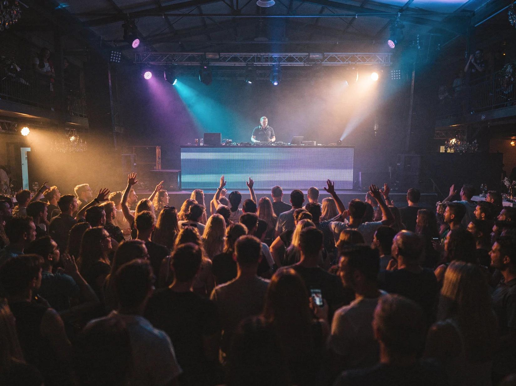 Volle dansvloer bij een trance-DJ in een grote club met blauwe en paarse lichtstralen