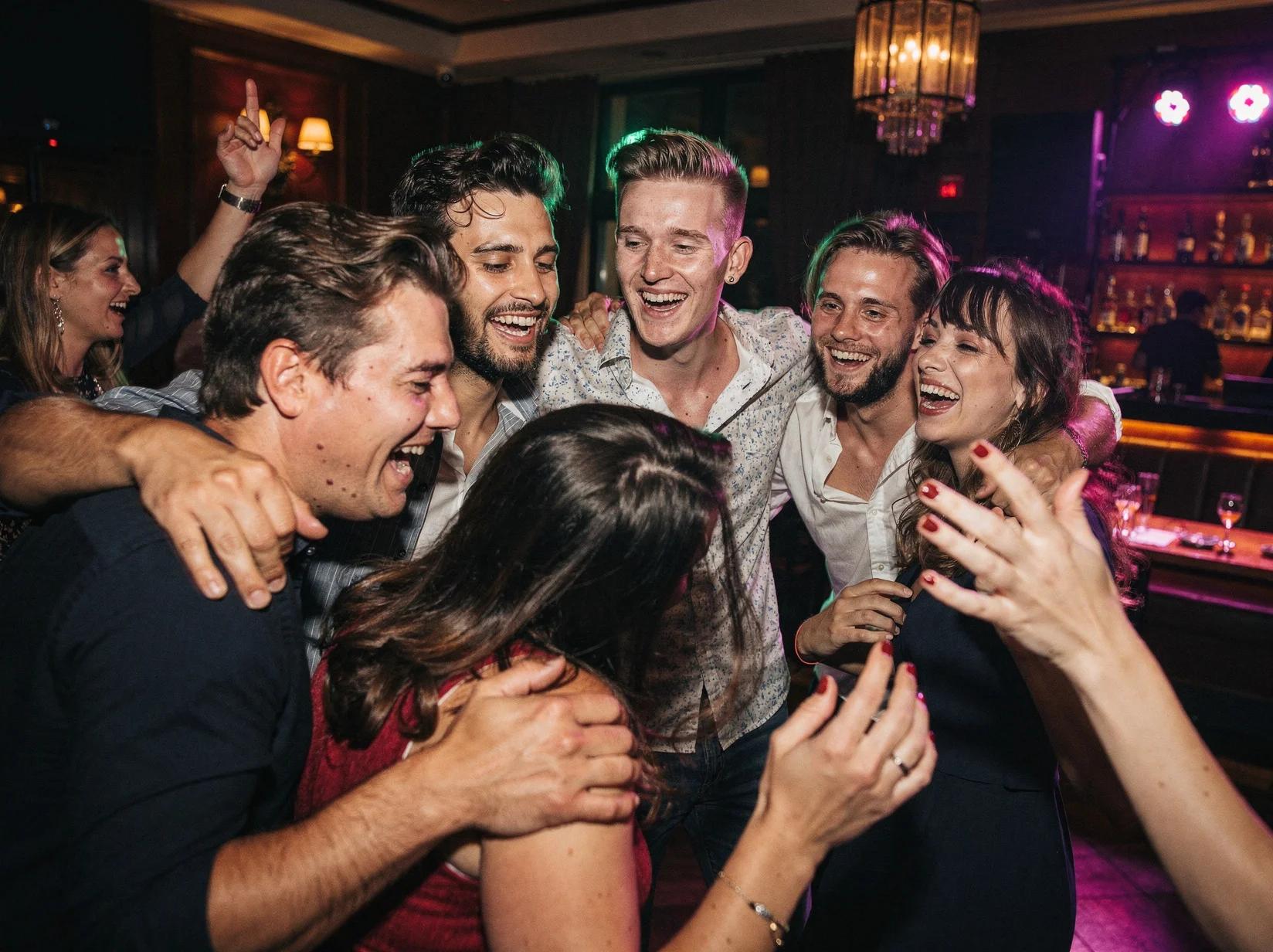Vrienden dansen dicht bij elkaar op een vrijgezellenfeest terwijl de flits het moment vastlegt