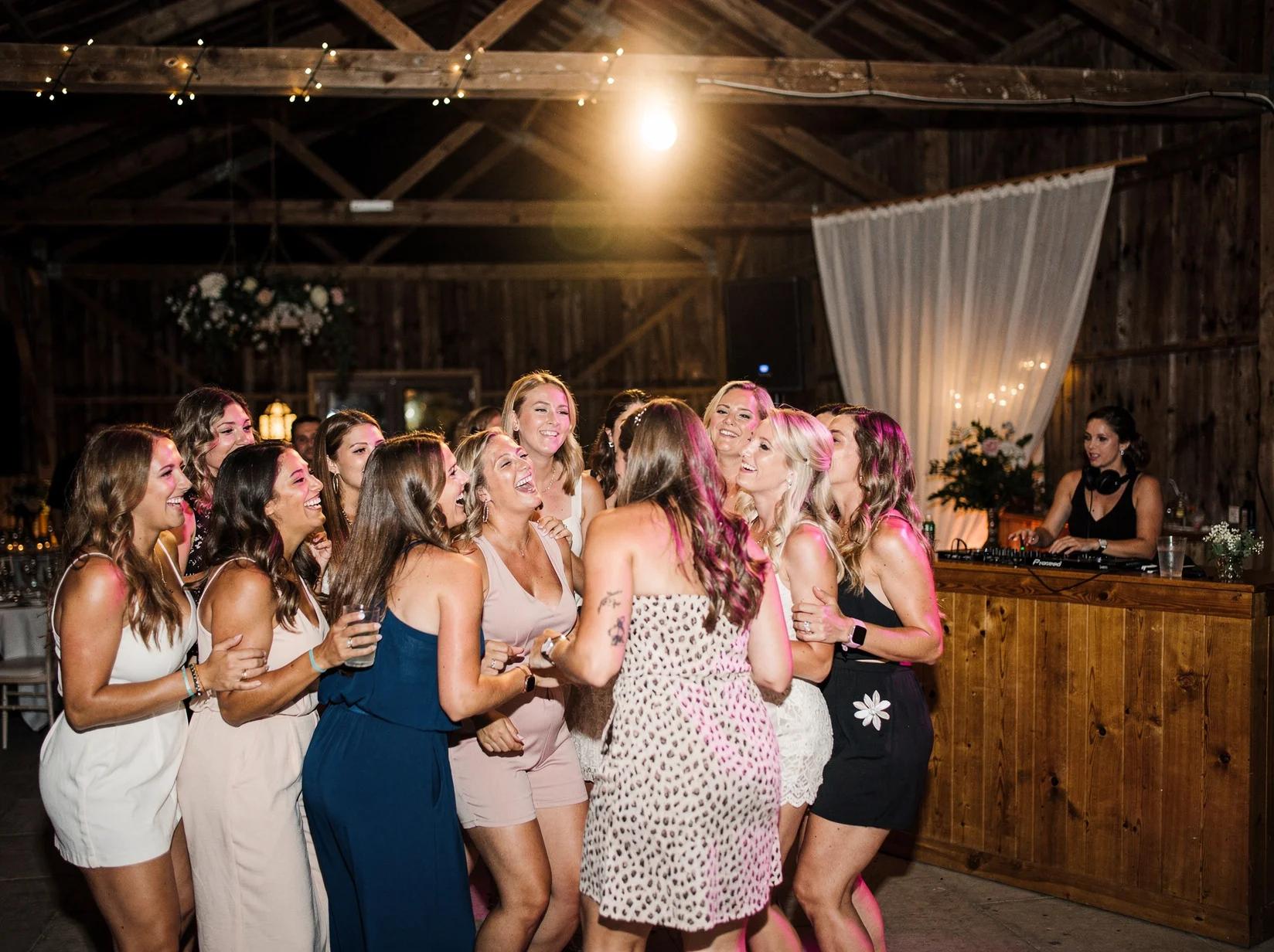 Vriendengroep danst uitgelaten tijdens de feestavond van een weekend weg met een DJ in een landelijke evenementenschuur